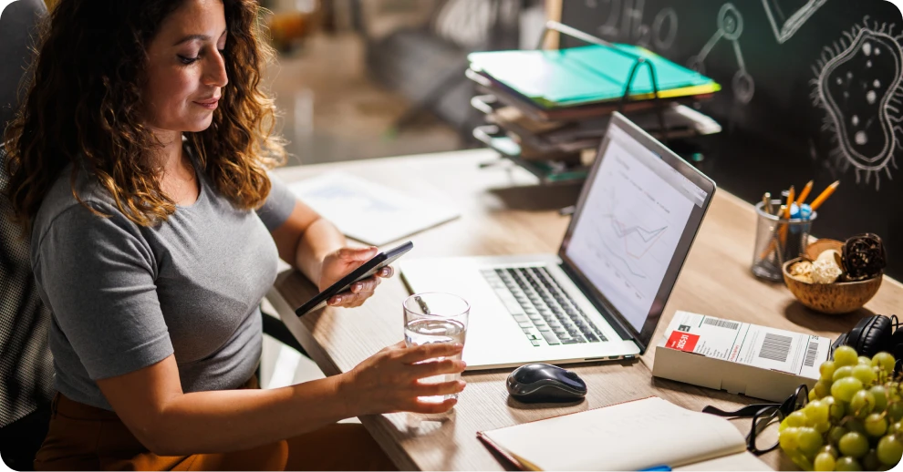 Woman working on a laptop and holding a glass of water