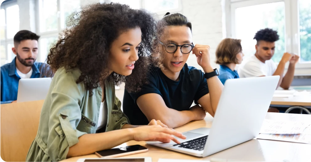 Students inside a classroom studying on a laptop