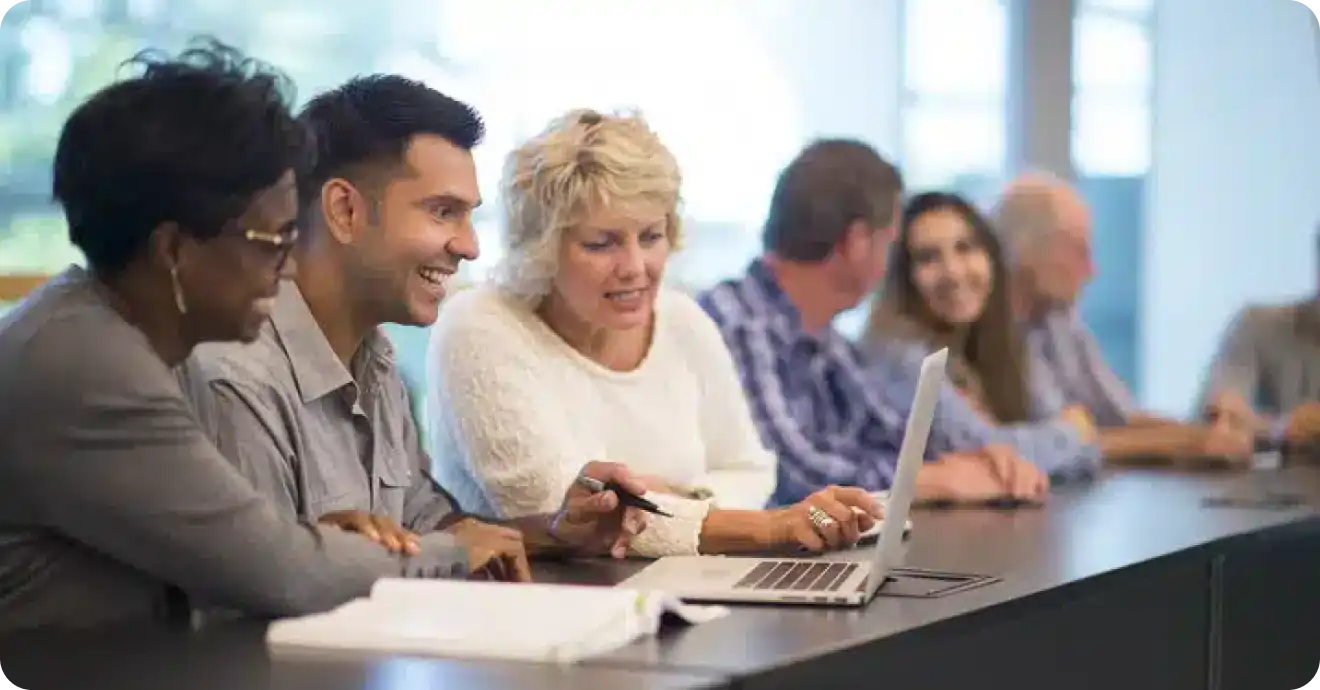 Group of coworkers looking at a laptop, having a discussion at work