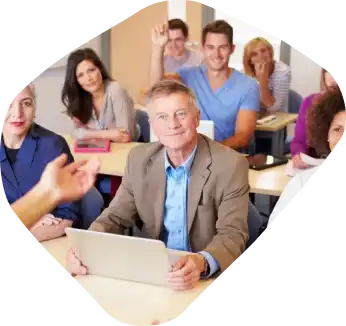 Old man surrounded by his staff in a classroom